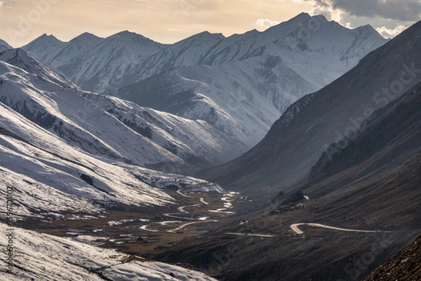 Obraz Winding Stream in a Snow-Covered Mountain Valley at Sunset