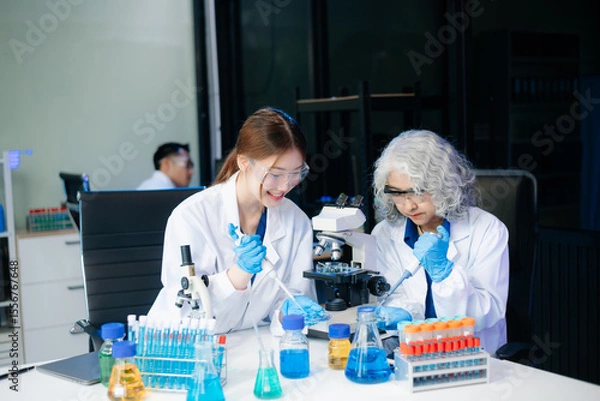 Fototapeta Scientists in lab coats collaborating with test tubes, flasks, and microscopes in a modern lab.