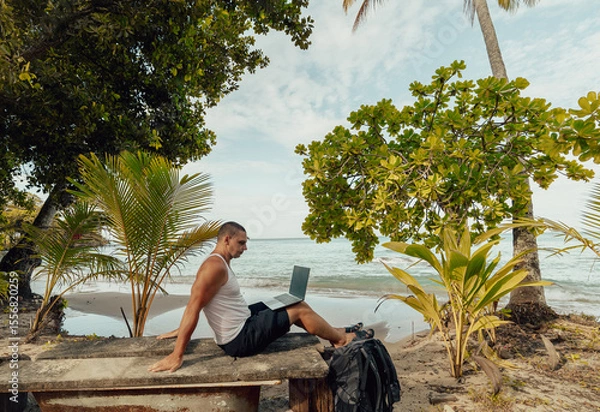 Fototapeta Man using laptop on the beach 