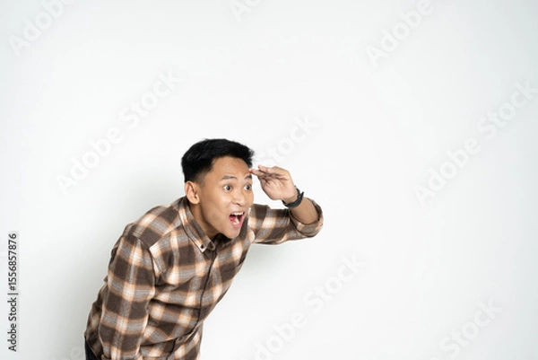Fototapeta A cheerful young man wearing a plaid shirt looks forward with enthusiasm while indoors. The image features bright expressions, conveying happiness, anticipation, and fun.