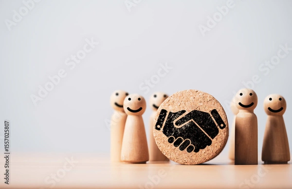 Fototapeta Wooden figures with smiling faces, symbolizing collaboration and teamwork, centered around a handshake icon on a cork circular base, representing partnership and mutual agreement.