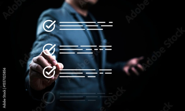 Fototapeta A person in a suit is checking items off a digital list. They hold a mobile phone in one hand while marking off completed tasks, representing organization and productivity in a professional setting.