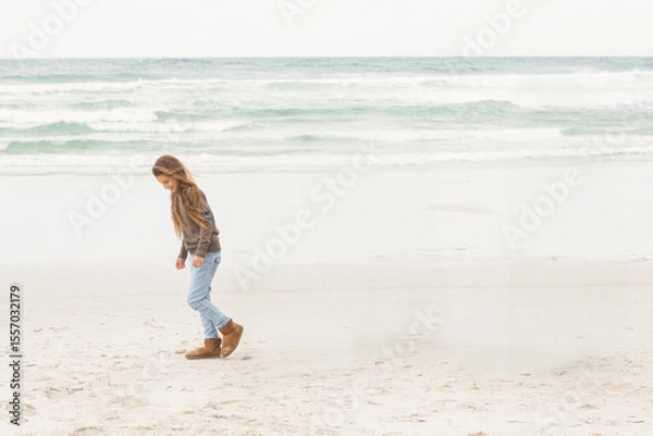 Obraz Child girl walking on sandy beach leaving footprints in wet sand near calm waves, copy space