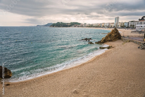 Fototapeta Landscape of Lloret de Mar with Playa de Fenals beach and sea on a cloudy day. Costa Brava coast in Spain.