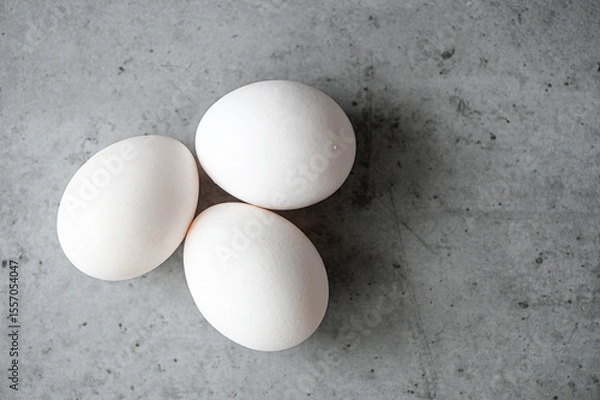 Obraz Top view of three white eggs on gray table