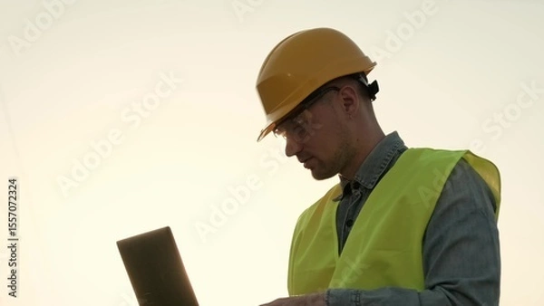 Fototapeta Power line inspector using laptop during transmission tower audit