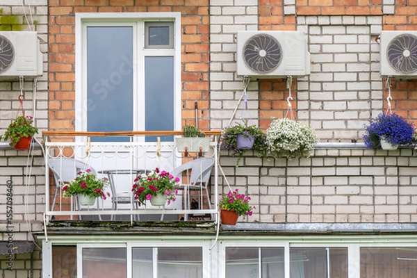Fototapeta Balcony of an apartment building with a table and chairs decorated with flowers in pots and boxes.
