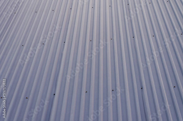 Fototapeta Sleek industrial blue gray corrugated metal roof texture with strong parallel lines and fasteners offering a modern abstract architectural background