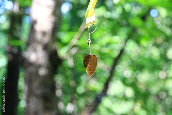 Fototapeta A golden heart-shaped paper mobile with a green bokeh background.