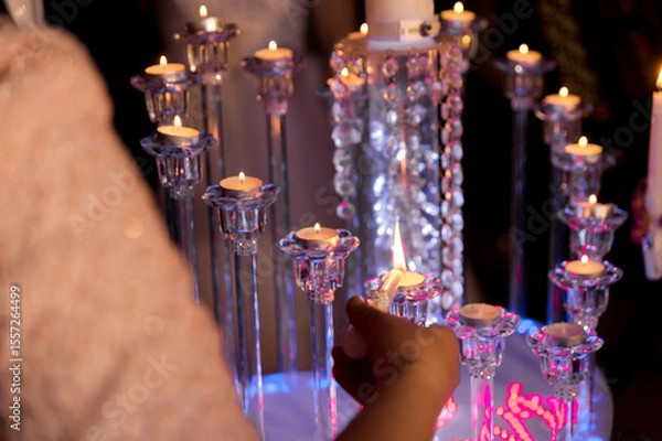 Fototapeta Lighting festive candles. Guests light decorative candles at a joyful gathering, creating an enchanting atmosphere with soft illumination.