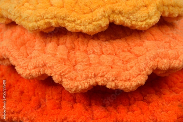 Obraz A close-up shot reveals three layers of soft, textured fabric in shades of yellow, orange, and dark orange, arranged in a ruffled pattern