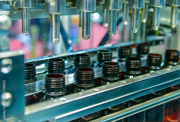 Fototapeta Glass bottles in a conveyor belt on a high quality automatic vertical filling machine. In the factory production line