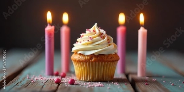 Fototapeta A single vanilla cupcake, adorned with delicate pink sprinkles and creamy frosting, sits serenely amidst four gently glowing pink candles on a rustic wooden surface.