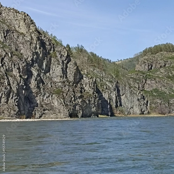 Fototapeta This breathtaking landscape showcases a powerful river winding through rugged mountains, featuring striking rock formations and lush greenery, perfect for nature lovers and outdoor enthusiasts.