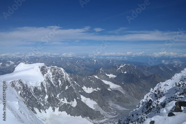 Fototapeta A stunning rock formation covered in snow, set against a clear blue sky with fluffy clouds in the background, creating a peaceful and breathtaking mountain landscape.