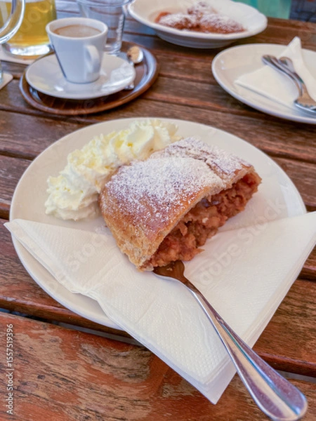 Obraz A slice of apple strudel with a golden-brown, flaky pastry crust dusted lightly with powdered sugar.