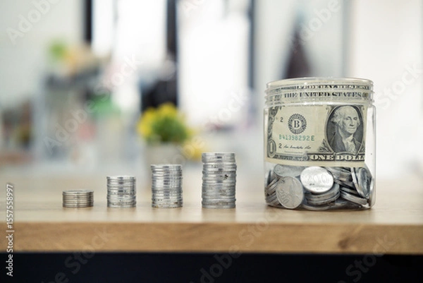 Fototapeta Progressive stacks of coins symbolizing savings growth beside a jar filled with money, emphasizing financial goals and stability. Ideal concept for investment, saving, and wealth-building themes.