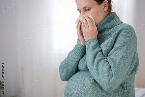 Fototapeta Expecting mother using tissue while having cold during pregnancy. Caring for health while experiencing common illness at home.