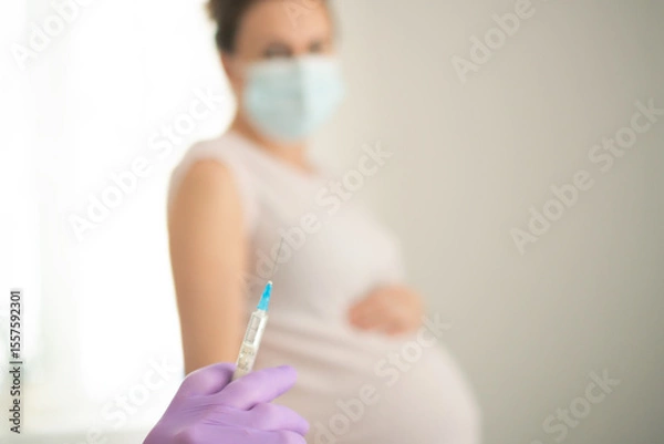 Fototapeta Healthcare worker administering vaccine to expecting mother. Focused shot on medical procedure protecting both maternal and newborn health through immunization.