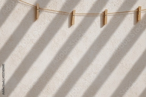 Obraz Diagonal shadows of clothespins on beige wall in sunlight