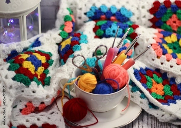 Fototapeta A cup and a saucer with clews balls of yarn wool and crocheted blanket handmade craft bright photo	
