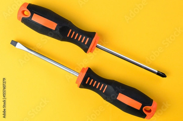 Fototapeta Cross and flat screwdrivers on bright yellow background isolated closeup tools