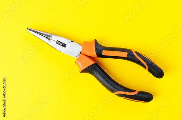 Fototapeta Close-up of metal pliers on vibrant yellow background with sharp details