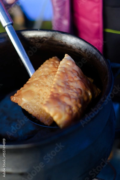 Fototapeta Woman preparing and frying empanadas and sopaipillas with cheese at a food truck