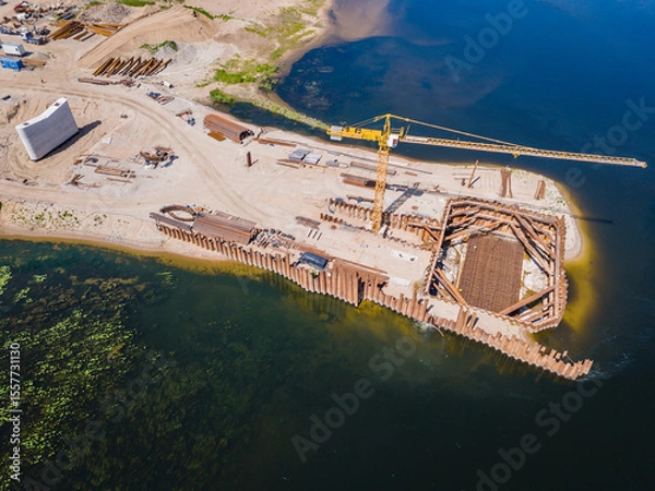 Obraz Construction site of new modern bridge construction in Kaunas, Lithuania. Aerial drone view of bridge connecting two shores of a river. Work progress