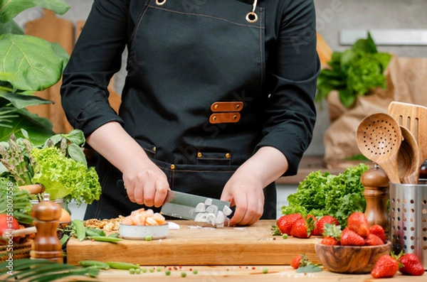 Fototapeta chef skillfully chopping onion, vegetables and arranging fresh ingredients on a cutting board in a vibrant kitchen setting.