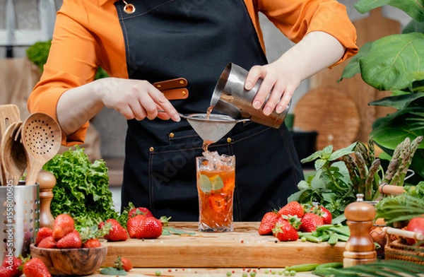 Fototapeta Chef prepares a refreshing herbal nojito drink with fresh strawberries and basil in a vibrant kitchen setting