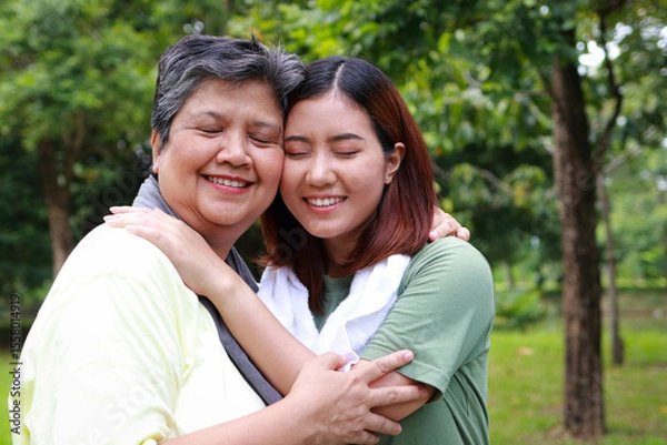 Obraz Elderly mother and daughter exercising together in the park, they hug each other and smile happily. Elderly care. Sports concept.