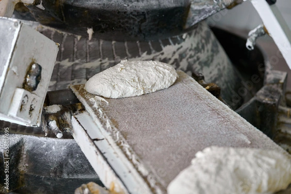 Fototapeta Dough being transported on conveyor belt in a baking facility during production process