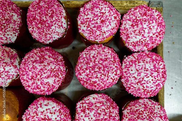 Fototapeta Traditional Russian kulich bread with vibrant pink sprinkles ready for Easter celebrations in a bakery setting
