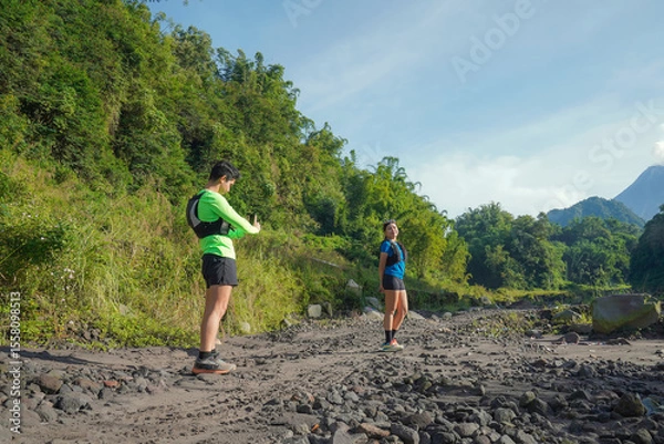 Obraz Asian Couple Trail Running and Taking Photos in Lush Nature Landscape