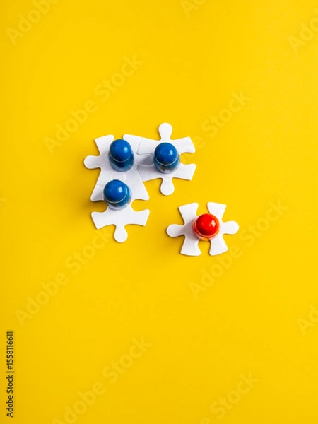 Obraz Leadership, unique and different, stakeholder, business teamwork, team building concept. Red peg doll, human figure standout from blues, standing on white jigsaw puzzles, vertical yellow background.