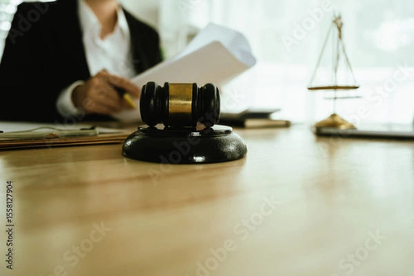 Obraz Lawyer sitting at desk in modern office reviewing and signing legal documents related to finance, equity and contractual agreements in business law.