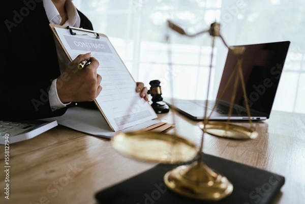 Obraz Lawyer sitting at desk in modern office reviewing and signing legal documents related to finance, equity and contractual agreements in business law.