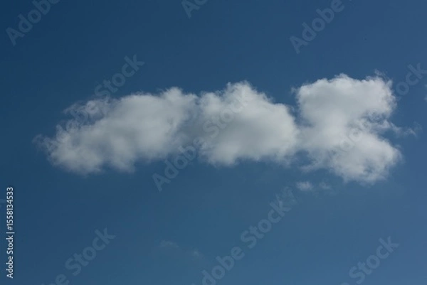 Fototapeta Elongated white cloud formation is stretching across deep blue sky in flat design, copy space