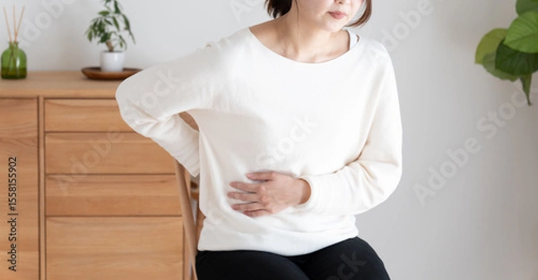 Obraz お腹と背中を押さえる体調不良の女性