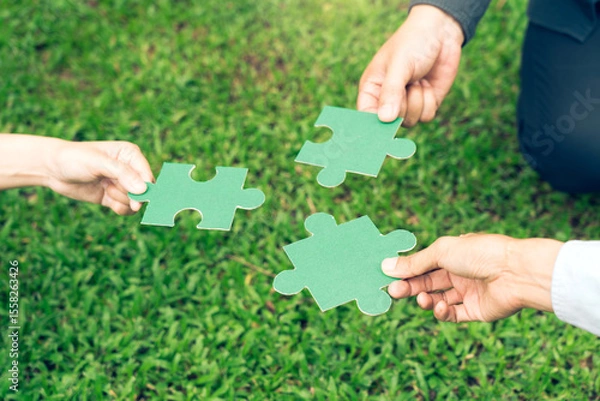 Fototapeta group of business people assembling jigsaw puzzle. The concept of cooperation, teamwork, help and support in business.