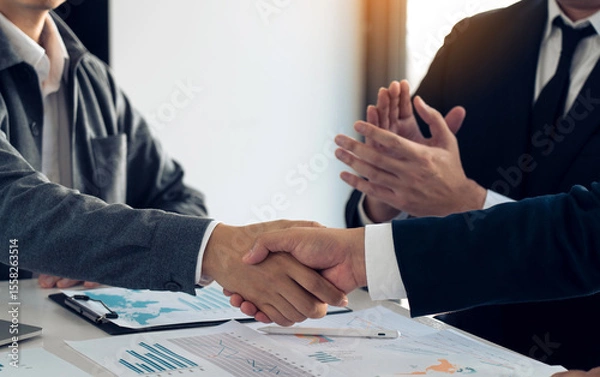 Fototapeta Businessmen shaking hands while completing work.