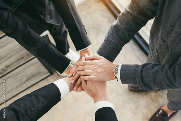 Fototapeta Close up of group of business people joining their hands together in unity.