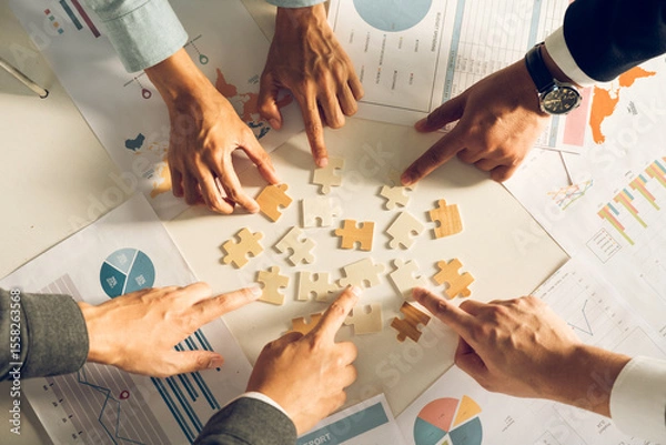 Fototapeta The concept of teamwork and partnership. Businessman's hands putting together puzzle pieces in the office and join together in a jigsaw puzzle team. Charity. Volunteers. Business unity as a team.