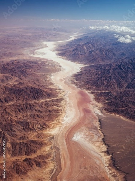 Fototapeta Low-altitude aerial view of Desert's white lake with pink salt, mountains, rivers and ripples.