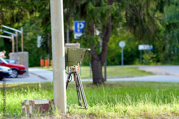 Fototapeta Speed Radar. Mobile speed control camera. Speed radar on tripod positioned near street light post for traffic enforcement and monitoring. Traffic control device. Automated vehicle speed control