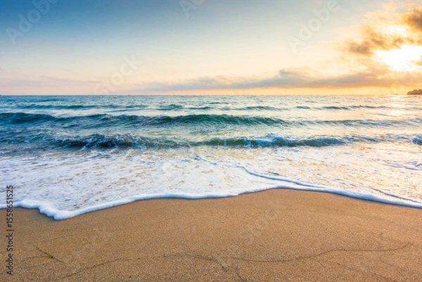 Obraz empty beach in the forenoon. beautiful landscape at the black sea. waves washing the sand on the shore. foam on the coast. clouds glowing in morning light. calm summer vacation and travel destination