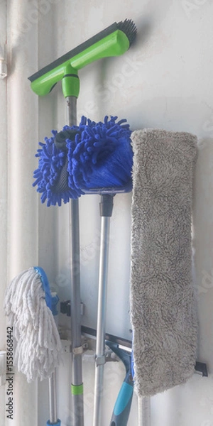 Fototapeta Cleaning tools organized on a wall, showcasing mops and dusters in a tidy storage space for household chores
