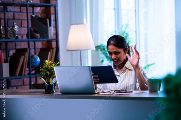 Fototapeta Indian employee working on tablet at office desk, using touch screen for business task