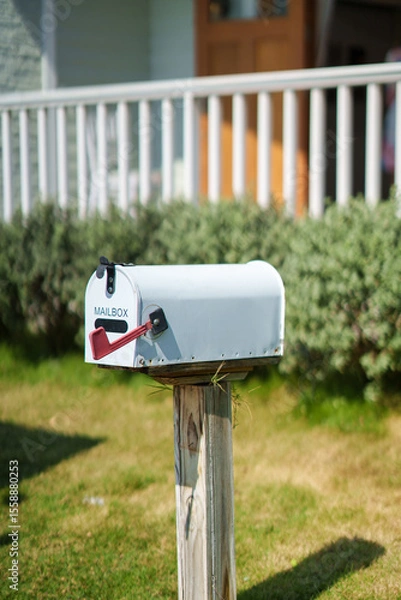 Fototapeta White american mailbox set on wooden post at front of house